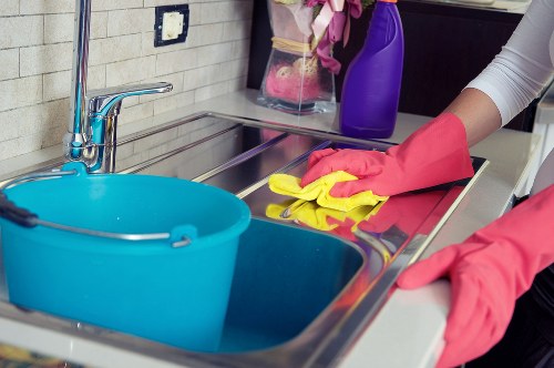 Cleaner in SW3 polishing kitchen surfaces in a modern home